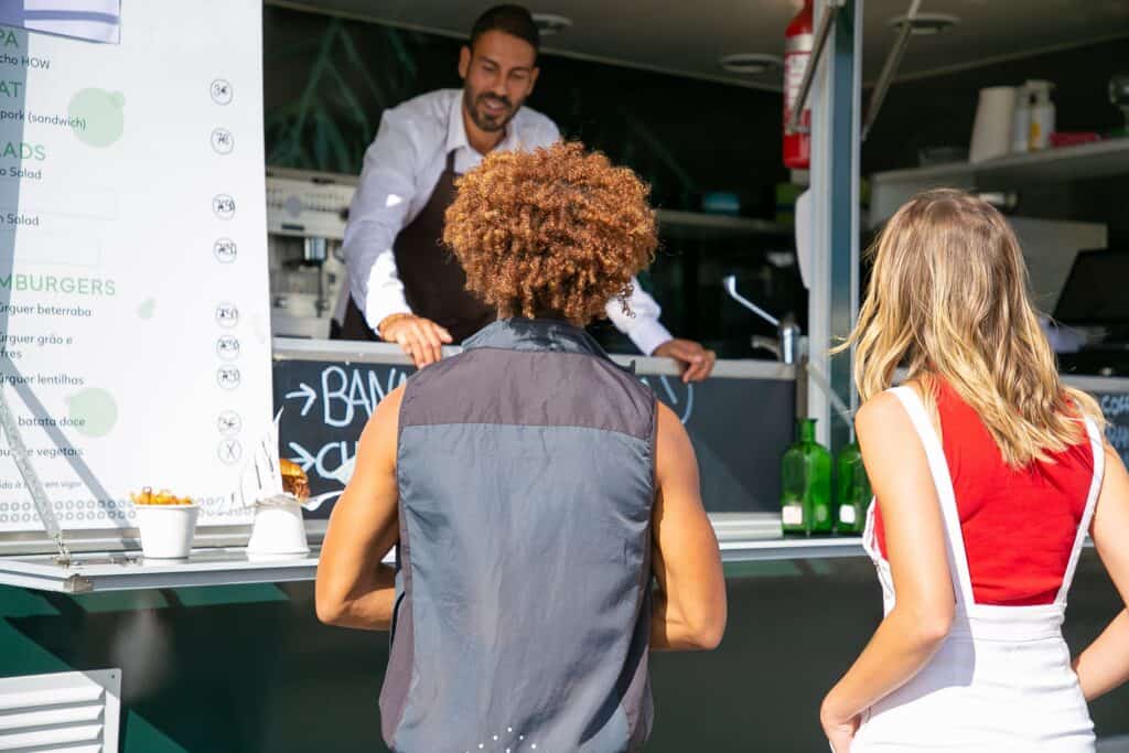 Food truck vendor serving a customer at the window, a guide to food truck permits