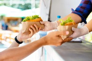 Food cart insurance: vendor handing food to a customer at an outdoor stand