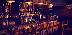 How to open a small bar: empty neighborhood pub with wooden bar stools and draft taps